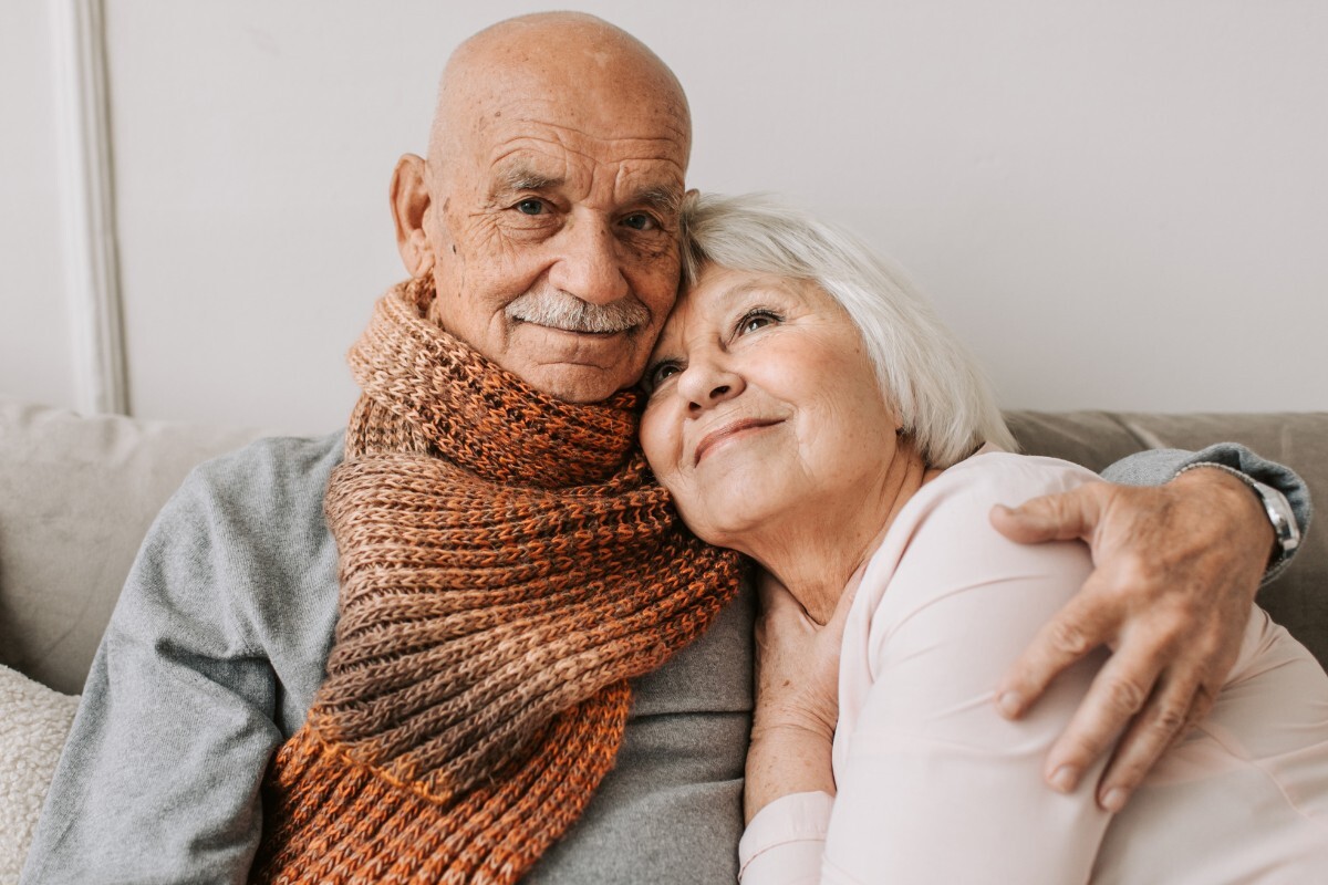 Elderly couple cuddling on a couch at home