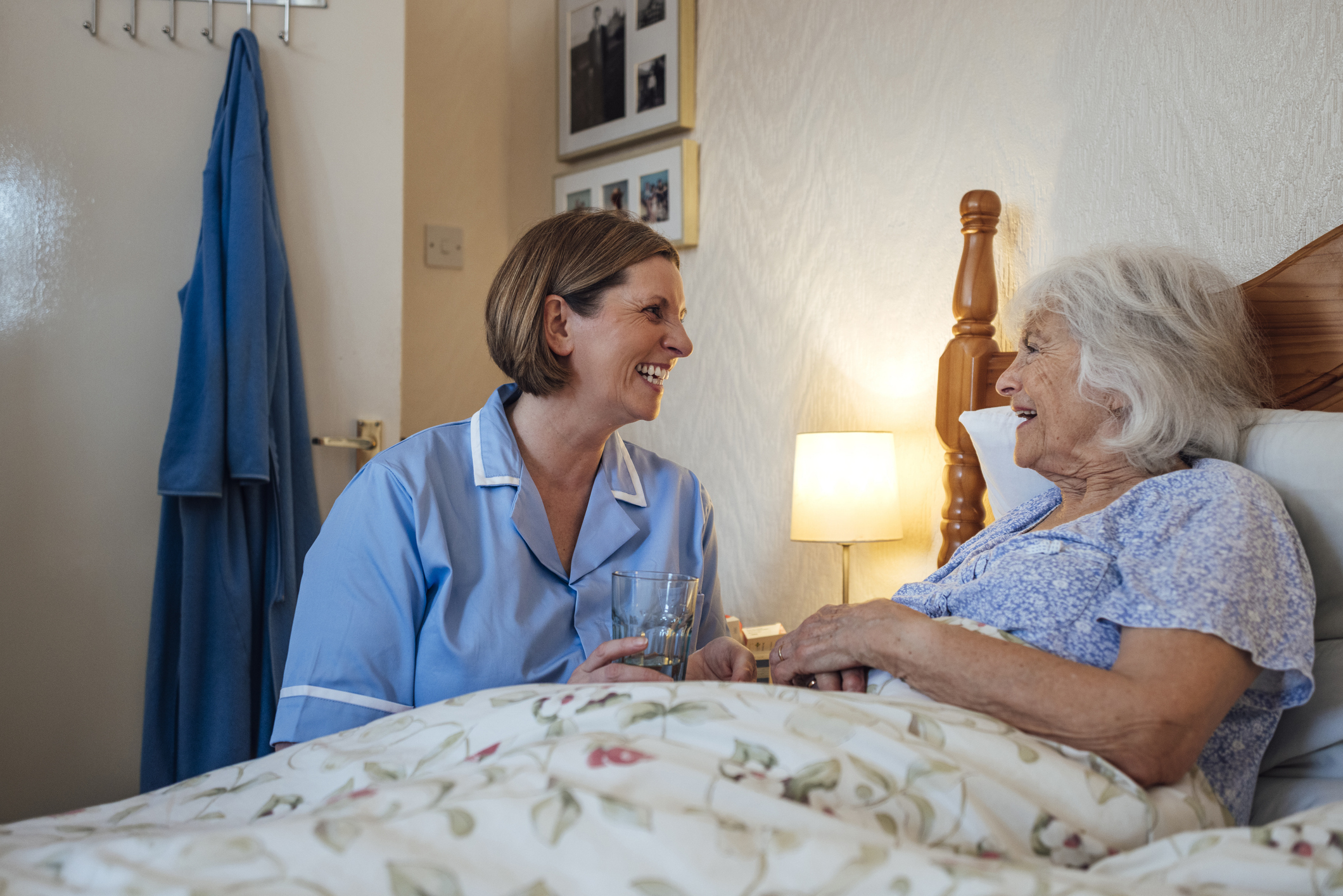 nurse with an older woman who's in bed
